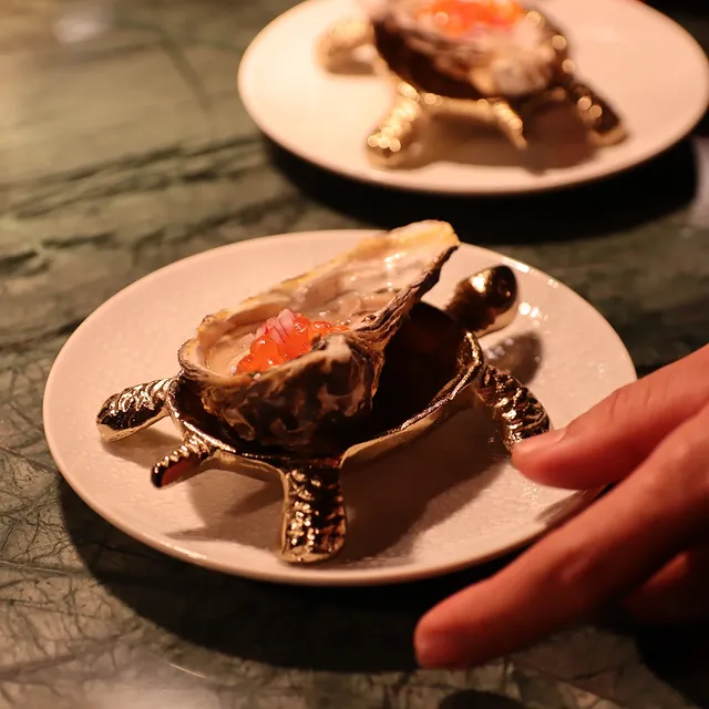 Ostra servida em suporte artístico dourado